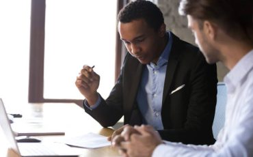 African american businessman reading documents at meeting, black client or customer considering contract terms before signing checking legal paper law conditions preparing to make financial deal